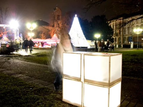 Leuchtende Würfel auf einer Wiese vor einem beleuchteten Weihnachtsbaum