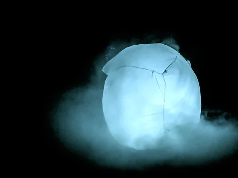 Leuchtende Skulptur aus Stoff und Nebel bei Nacht